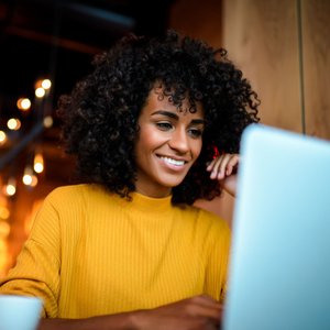 black woman with yellow sweater using laptop
